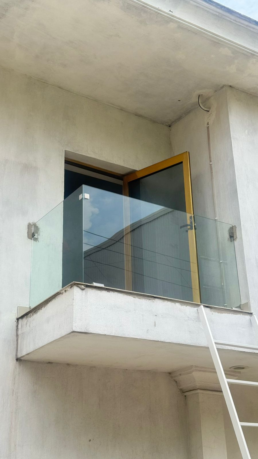 Barandal de cristal en un balcón exterior frente a una puerta. Trabajo real de Vidrio y Aluminio EG.
